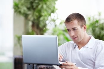 Young attractive man with a laptop in a cafe