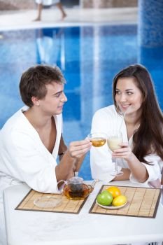 The young man with tea and attractive girl in pool