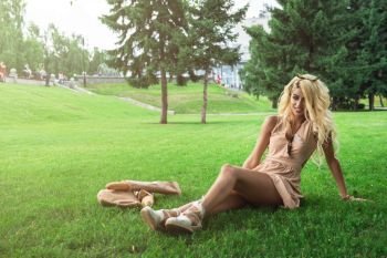 Rest in park, food, and people concept - beauty blonde young woman resting in the park. Beauty blonde alone young woman resting in the park