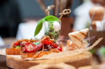Tasty tomato Italian bruschetta on toasted slices of baguette with spice herbs and basil on a wooden board. Catering concept. Tasty tomato Italian bruschetta