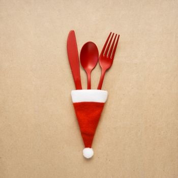 Creative concept photo of tableware christmas hat in on brown background.