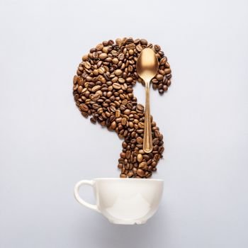 Creative food concept photo of cup of coffee drink beverage beans and golden spoon tableware on grey background.