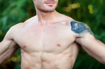 Attractive guy showing his muscles and a big tattoo on the shoulder