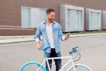 Casual guy next to a vintage bicycle with the mobile wearing denim shirt