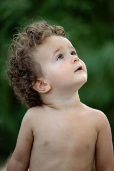 Beautiful baby with curly hair in the garden without t-shirt