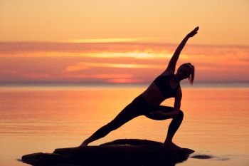 caucasian fitness woman practicing yoga on the beach at sunset. caucasian fitness woman practicing yoga