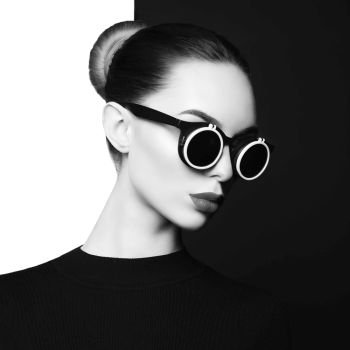 young sexy lady with black stylish sunglasses in black-and-white studio. beautiful woman with perfect lips and black lipstick pose in photostudio. Fashion portrait of fashionable model.