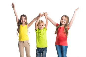 Happy smiling three children in colorful clothes holding raised hands isolated on white background. Happy children isolated on white