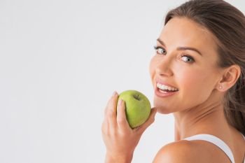 Beautiful woman with healthy white teeth holding green apple on white background. Woman holding green apple