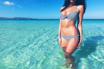 Pretty slim girl in bikini at tropical sea water. Pretty girl at the beach