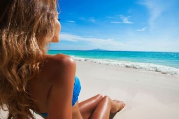 Happy tanned girl in bikini at seaside, blue sea water in background. Happy girl in bikini at seaside