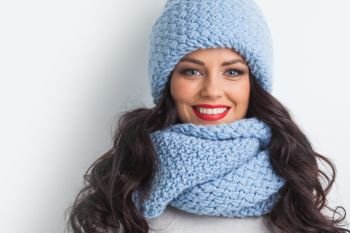 Beautiful woman in blue warm hat and scarf on white background. Woman in warm clothing