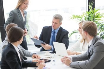 Mixed group of white collar workers at business meeting discuss documents, Business man reading contract at office table. Workers at business meeting