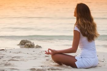 Young healthy woman practicing yoga on the beach at sunset. Yoga woman on beach at sunset