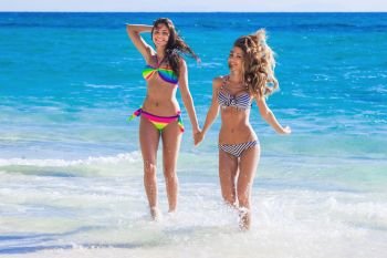 Happy smiling female friends running in sea waves. Feamle friends by the sea
