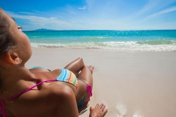 Young woman in bikini laying at seaside, rear view. Woman laying at seaside