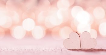 Two handmade wooden pink hearts on beautiful bokeh background. Vintage style. Love Valentine’s Day concept.. Two pink hearts on bokeh background