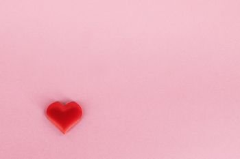 Valentine’s day red silk heart on pink paper background, love concept. Valentines day heart on pink