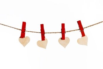 Small wooden hearts with red clothes pegs on a rope isolated on white background. Red hearts with clothes pegs on rope