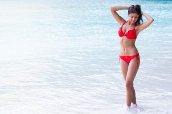 Beautiful smiling woman on summer vacation posing in front of the ocean in her red bikini. Woman on summer vacation