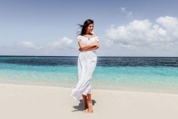 Woman in white dress walking on tropical beach, tropical sea on background. Woman in dress walking on beach