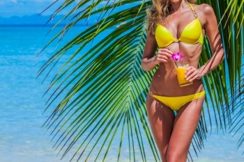 Beautiful slim woman in bikini holding cocktail over palm tree and sea beach background. Woman with cocktail on vacation
