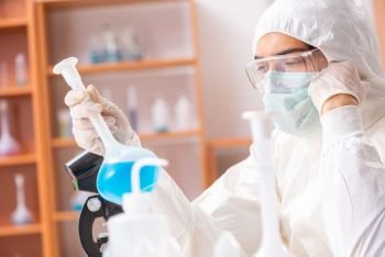 Young biochemist wearing protective suit working in the lab. The young biochemist wearing protective suit working in the lab