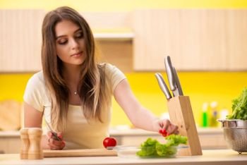 Young woman preparing salad at home in kitchen