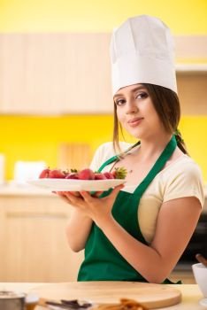 Young female cook eating strawberries