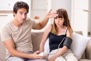 Husband checking wife’s blood pressure