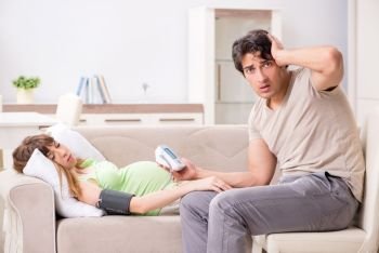 Husband checking pregnant wife’s blood pressure