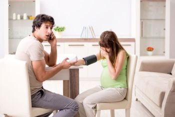 Husband checking pregnant wife’s blood pressure