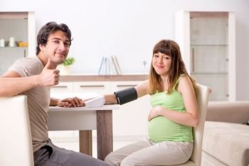Husband checking pregnant wife’s blood pressure. The husband checking pregnant wife’s blood pressure