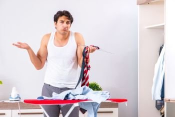 Young man ironing in the bedroom 