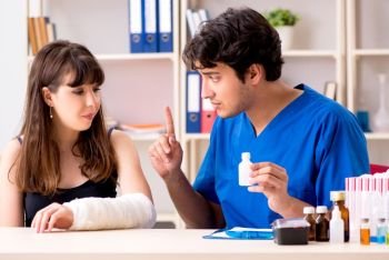 Young woman with bandaged arm visiting male doctor traumotologist . Young woman with bandaged arm visiting male doctor traumotologis