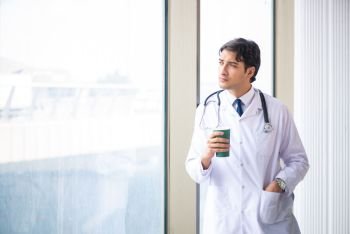 Young handsome doctor standing at the window 