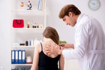 Female patient visiting young handsome doctor chiropractor . The female patient visiting young handsome doctor chiropractor 