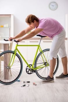 Man repairing his broken bicycle. The man repairing his broken bicycle