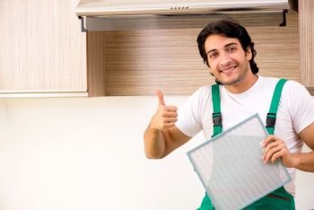 Young contractor repairing air-conditioner in kitchen