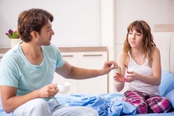 Young husband looking after sick wife in the bedroom 