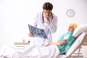 Young handsome doctor visiting female oncology patient 