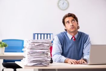Young handsome employee unhappy with excessive work  