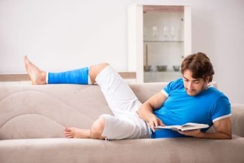 Leg injured young man on the sofa