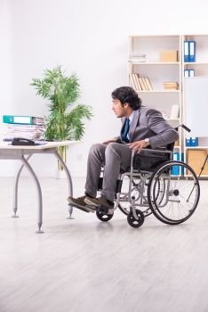 Young handsome employee in wheelchair at the office 