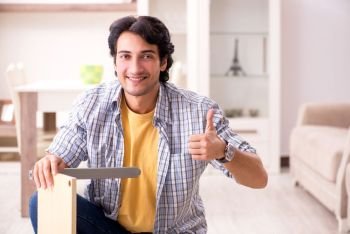 Young handsome man repairing chair at home 