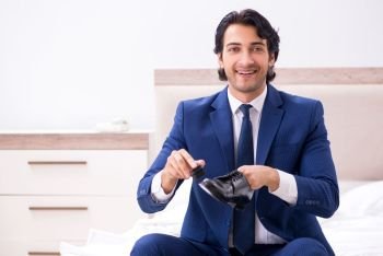 Young handsome businessman choosing shoes at home 