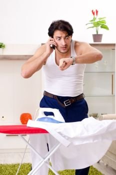 Young man ironing in the bedroom