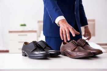 Young handsome businessman choosing shoes at home 