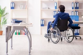 Young male employee in wheelchair working in the office 