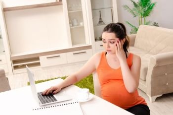 Young pregnant woman working at home 